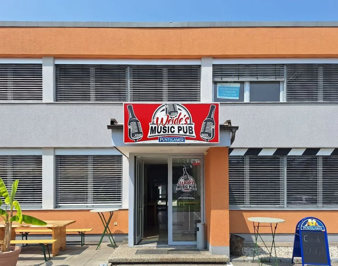 Leuchtkasten mit Puntigamer-Logo über dem Eingang eines Lokals, Fassade bei Tag