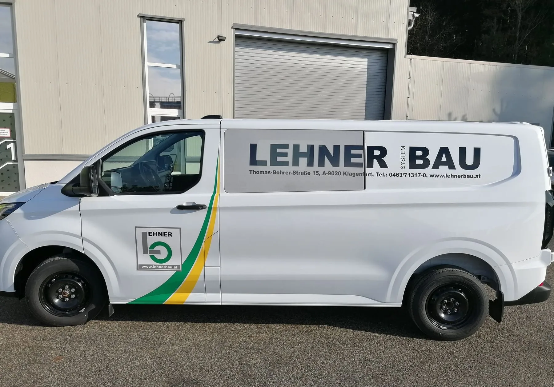 Transporter von Lehner Bau mit Logo und grün-gelbem Farbstreifen, Seitenansicht