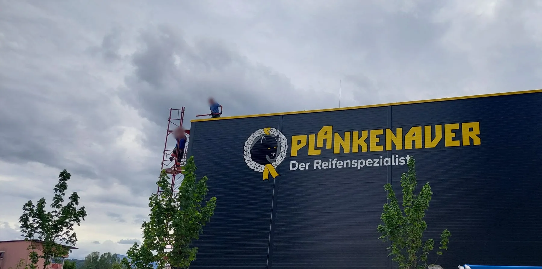 Montage des Schriftzugs Plankenauer Der Reifenspezialist, Monteure auf Gerüst und Dach