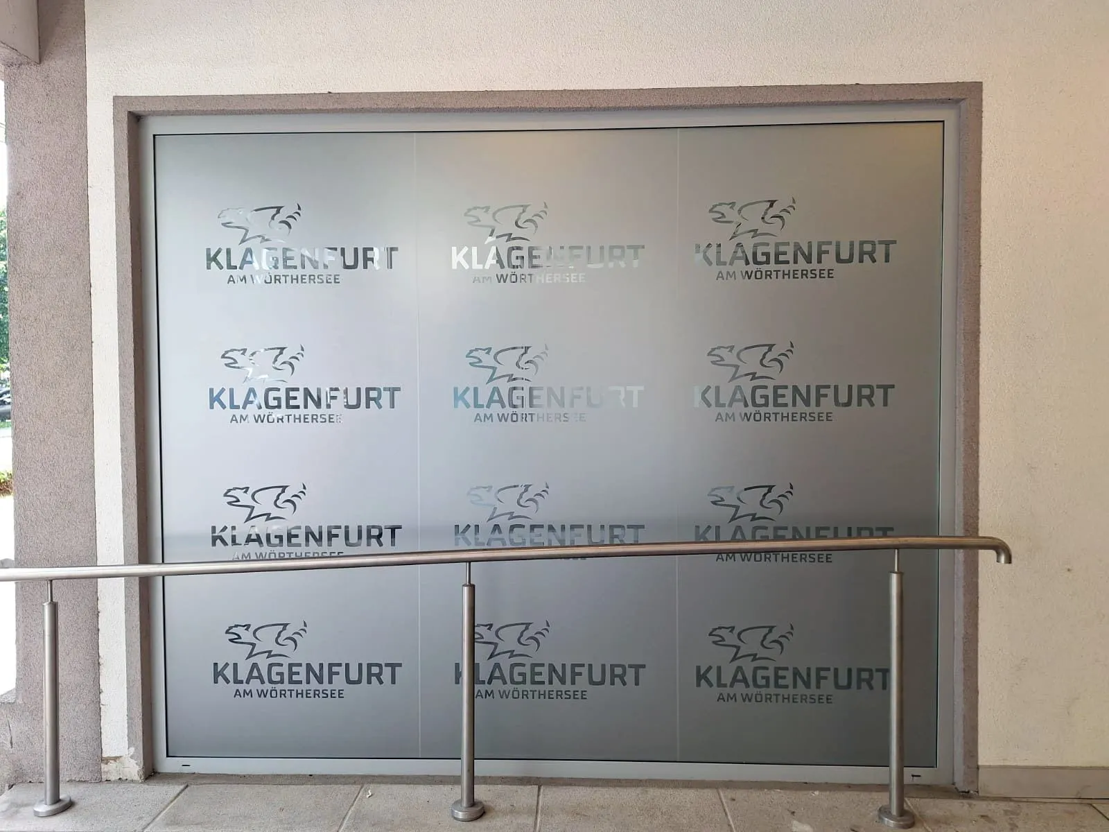 Satinato geplottet: Stadtlogo „Klagenfurt am Wörthersee“ als Rapport über eine große Glasfläche